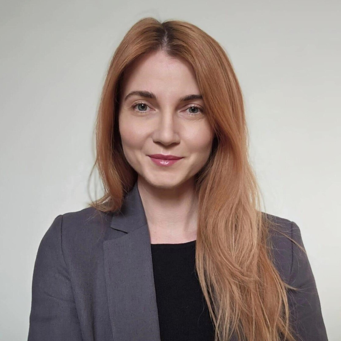 Ana Maria Ciufu, smiling, with long auburn hair and a dark blazer