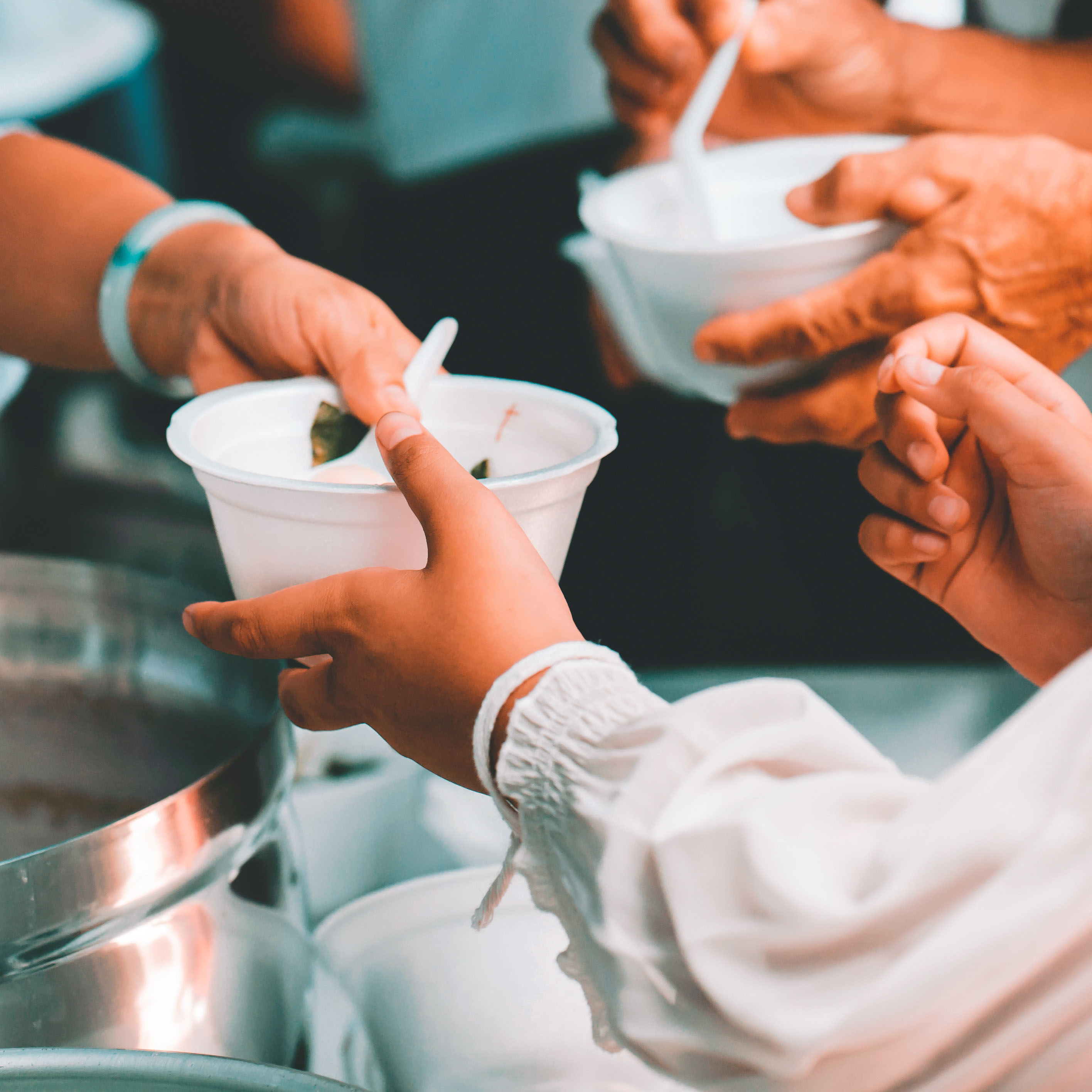 Hands serving soup into bowls during a community volunteering activity