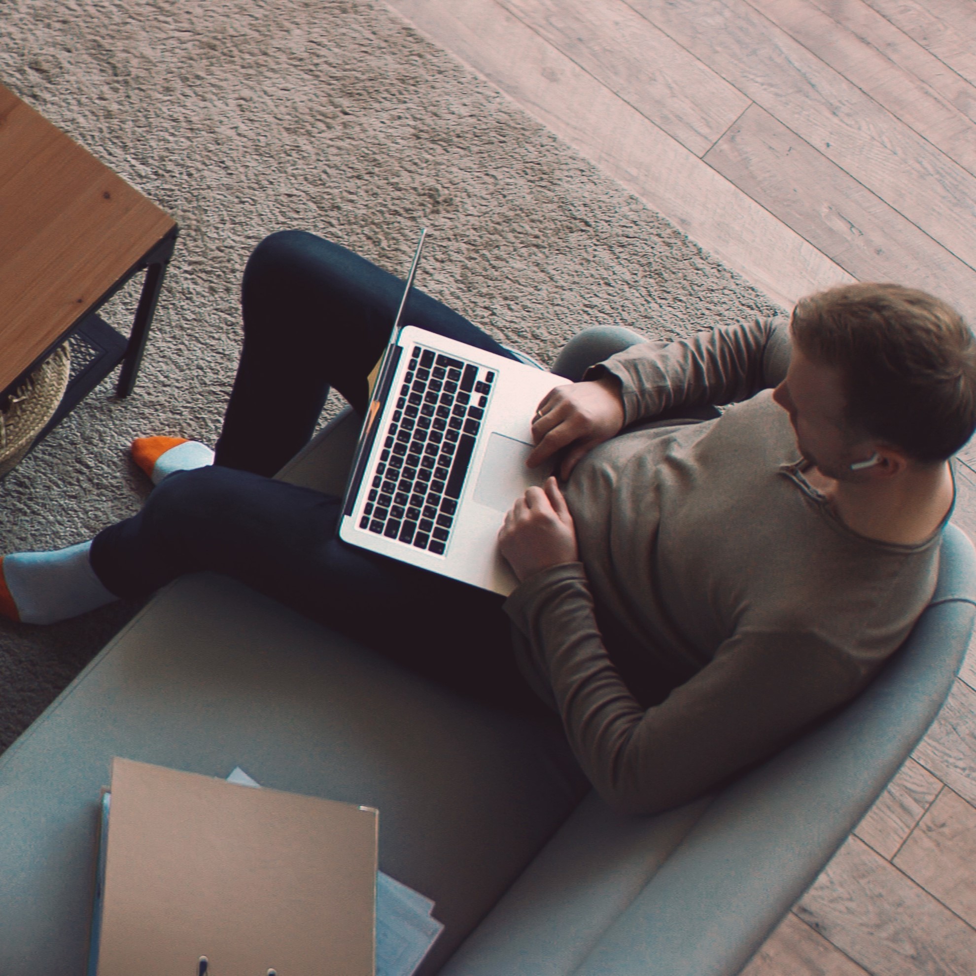 Person working remotely with a laptop on their lap in a cozy home setting