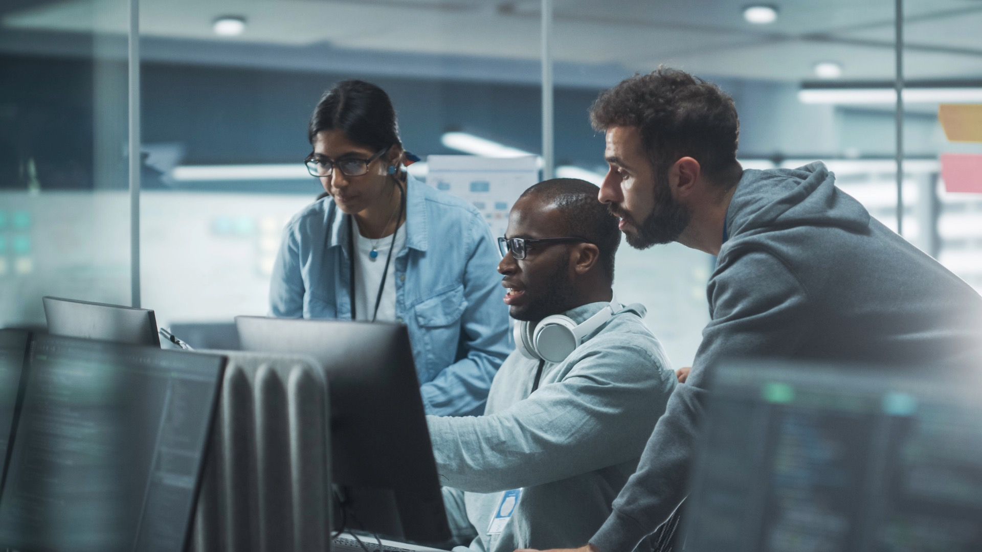 Focused team collaborating at computer screens in a modern IT workspace