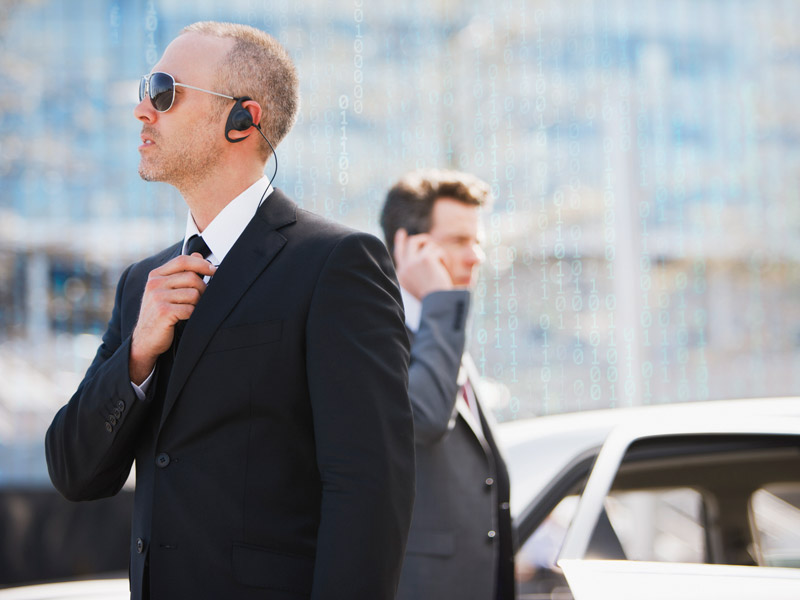 Sicherheitsmitarbeiter stehen vor einem Auto